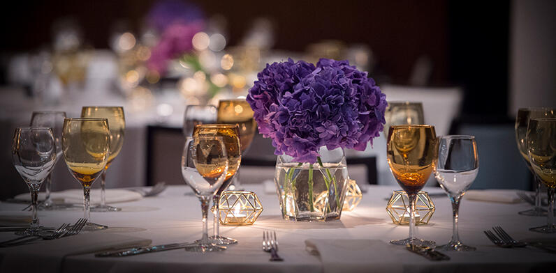 round tables set for dining with purple floral center pieces