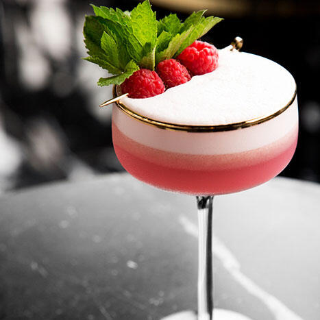 Pink cocktail with raspberries and mint on top