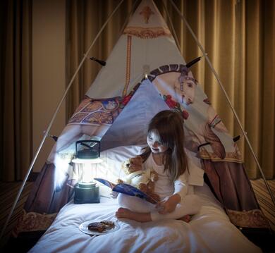 girl with teddy bear sitting in a teepee