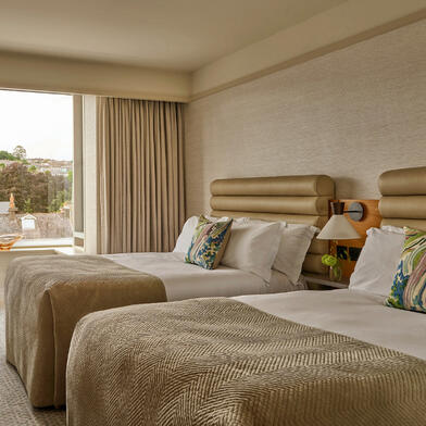 Guest room at The River Lee Hotel with two double beds, modern decor, and a beautiful river view.