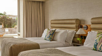 Guest room at The River Lee Hotel with two double beds, modern decor, and a beautiful river view.