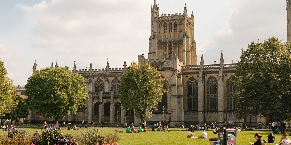 Lush green lawns and mature trees at Bristol University park in Clifton, with historic campus buildings in the background.