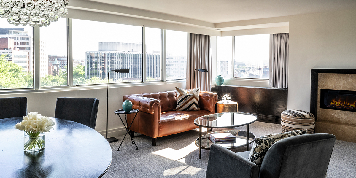The Signature Park View Suite living room, where modern seating meets large windows that frame the vibrant streets of Washington, D.C.