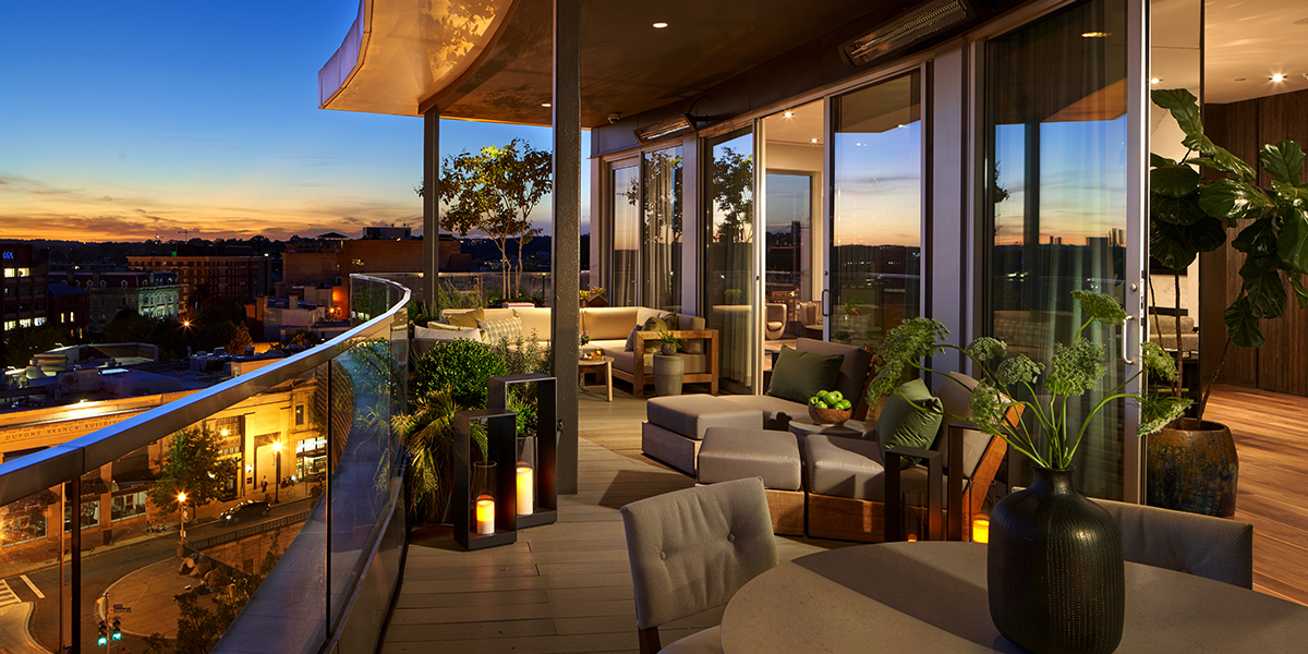 Evening view from a private Penthouse terrace in Washington, D.C., showing a glowing sunset over the city skyline with luxury outdoor seating.
