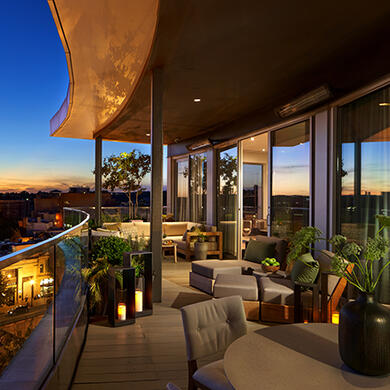 Evening view from a private Penthouse terrace in Washington, D.C., showing a glowing sunset over the city skyline with luxury outdoor seating.