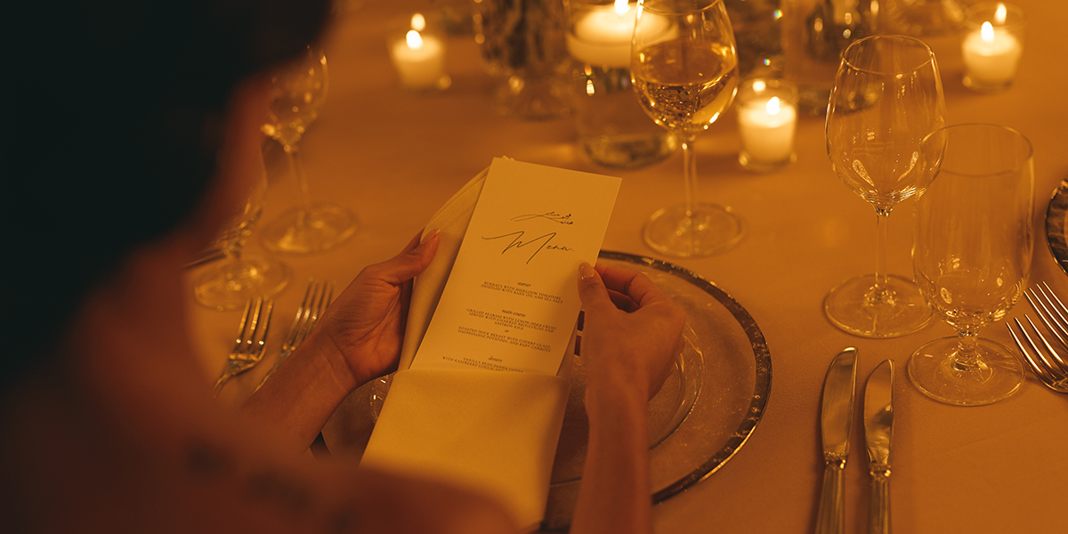 The romantic glow of a private dinner at The Dupont Circle, where a guest reviews a bespoke menu amidst a sophisticated table arrangement