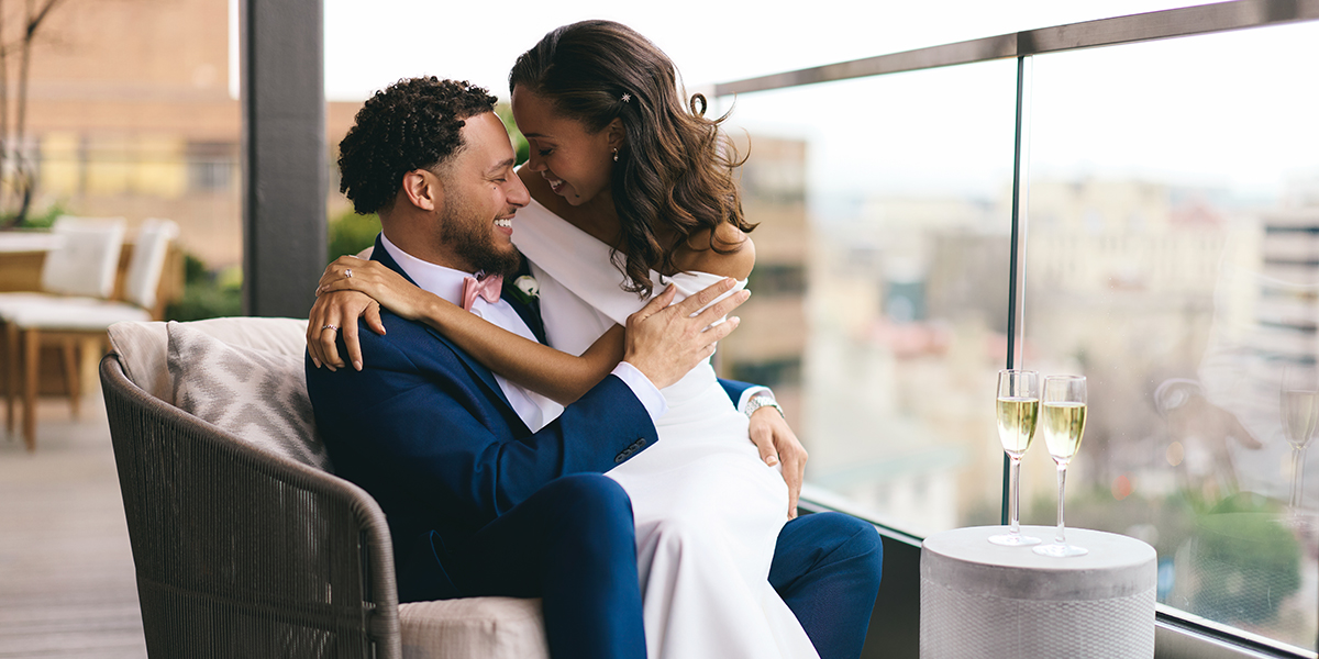 Newlyweds celebrating their marriage with a champagne toast on The Penthouse terrace at The Dupont Circle, featuring panoramic skyline views of Washington, D.C.