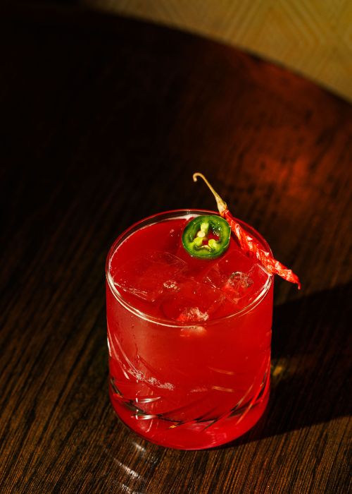 A red Beautiful Bird cocktail with a chili garnish, inspired by Lady Bird Johnson at Doyle Bar