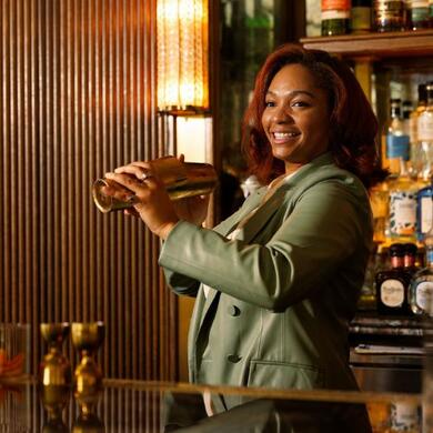 Smiling female bartender mixing a drink with a cocktail shaker at Doyle Bar.