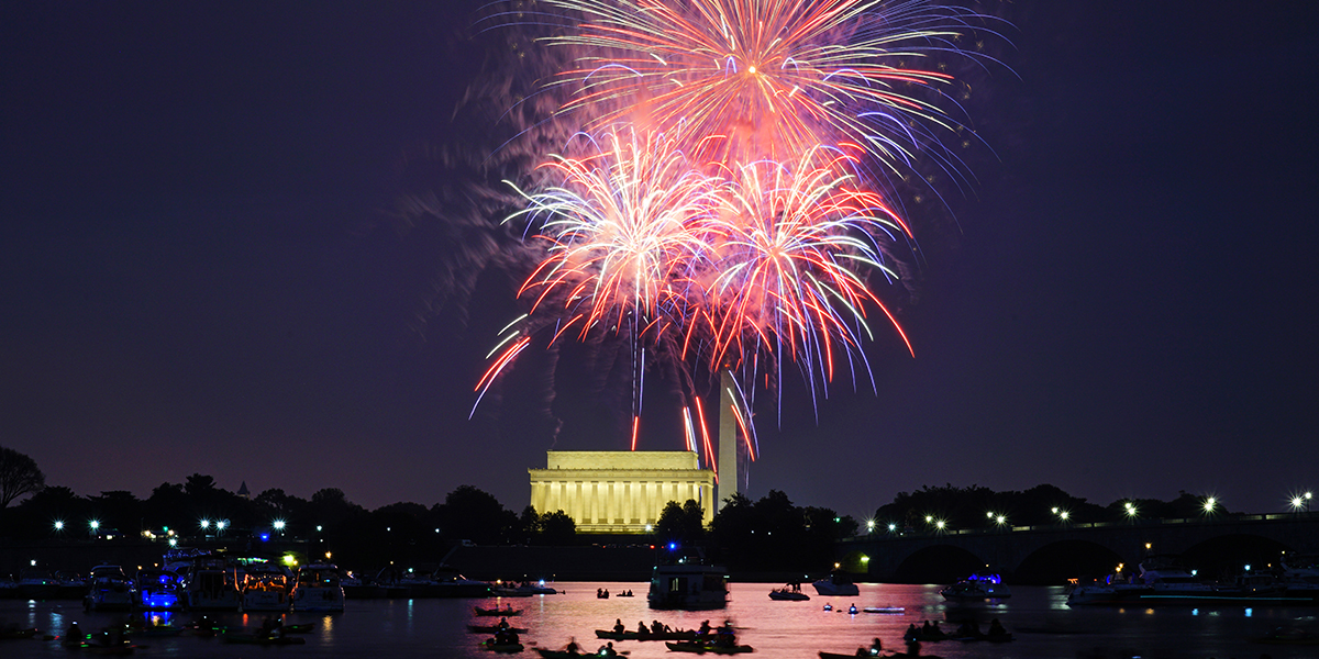 Fourth of July fireworks illuminating the Washington, DC skyline over the Potomac River.