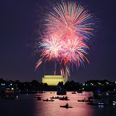 Fourth of July fireworks illuminating the Washington, DC skyline over the Potomac River.