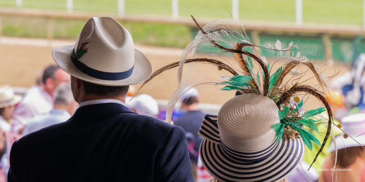 Close-up of a lady in a sophisticated, hat and a gentleman in a classic top hat, viewed from behind as they look out over the racecourse at Royal Ascot in Berkshire.