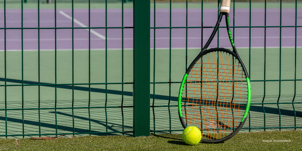 A yellow tennis ball and a tennis racket resting on the pristine green grass of a Wimbledon court