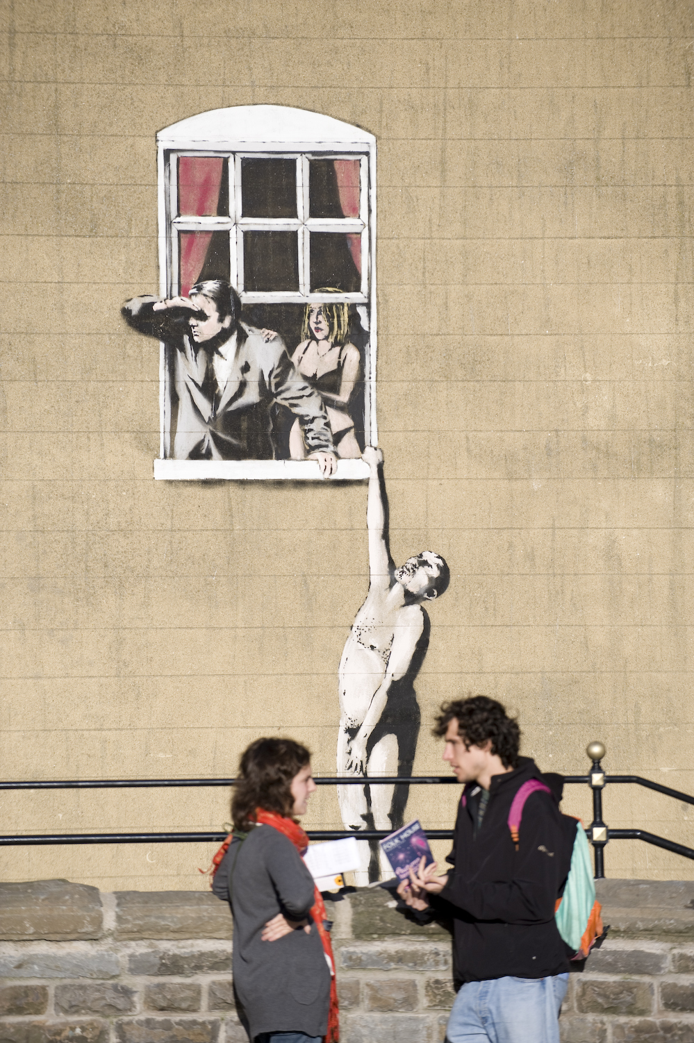 A couple standing beneath a vibrant painted wall, exploring Bristol's street art.