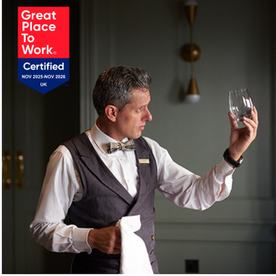 A close-up of a bartender ensuring a glass is spotless, symbolizing attention to detail, alongside the "Great Place to Work UK" recognition badge earned by The Doyle Collection teams.
