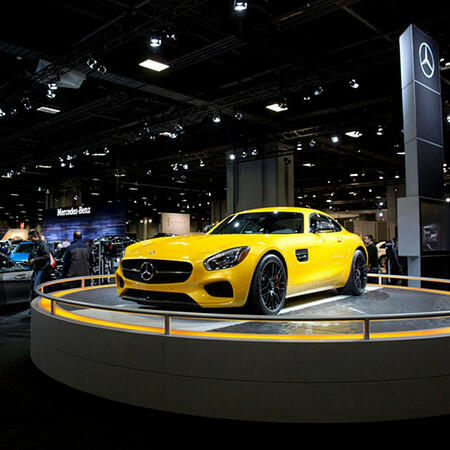 Side profile of a bright yellow Mercedes-Benz luxury car on the showroom floor at the Washington, D.C. Auto Show.