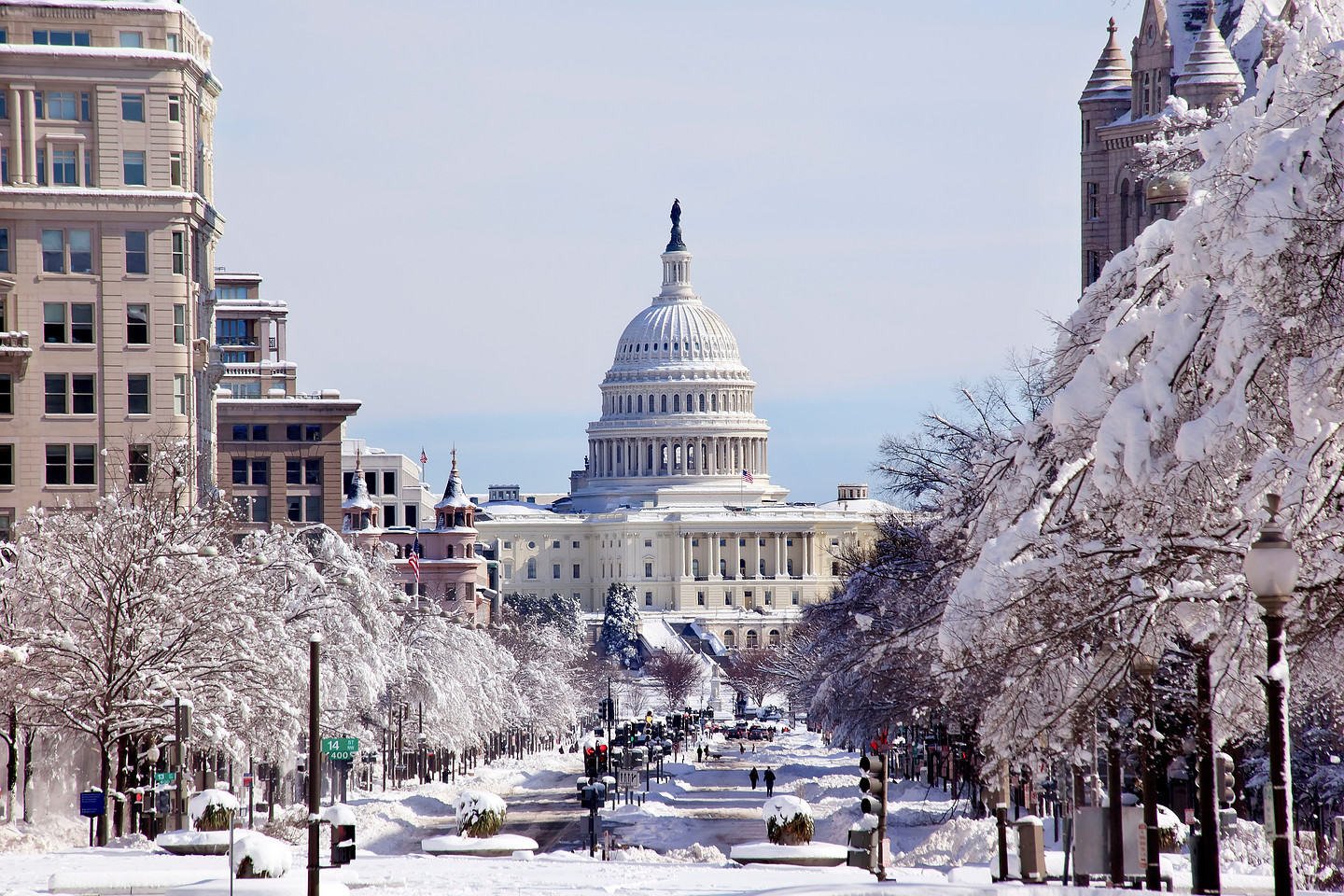 A serene winter scene of the U.S. Capitol, with the surrounding neighborhood streets and trees heavily laden with fresh snow.