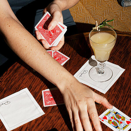 A cozy group of friends enjoying seasonal cocktails and playing cards at Doyle Bar, creating a festive winter atmosphere in a dimly lit, sophisticated setting.