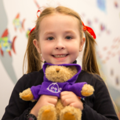 Little girl holding teddy bear at Gosh fundraiser