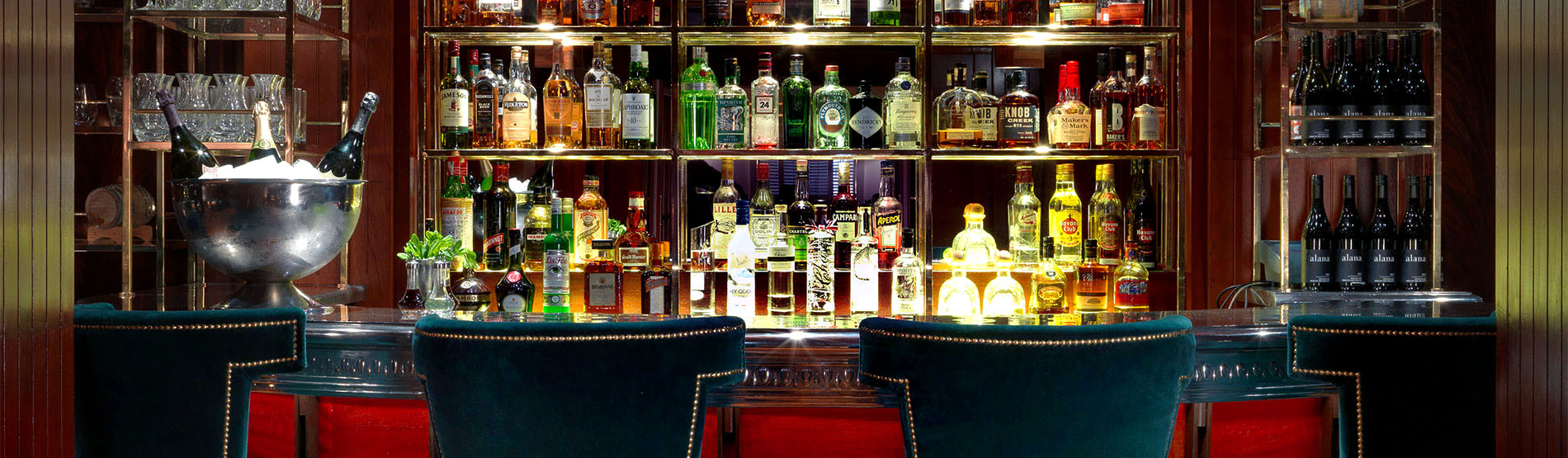 The bar at the Bloomsbury Club with green chairs and image of the bar with drinks
