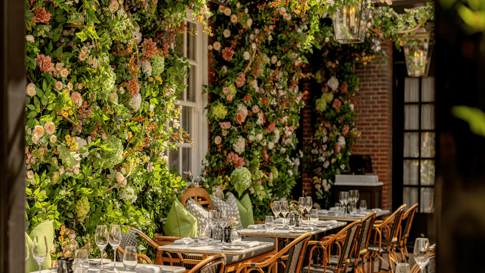 The colourful and inviting Dalloway Terrace at The Bloomsbury hotel adorned with hanging roses and flowers, featuring elegant tables ready for guests.