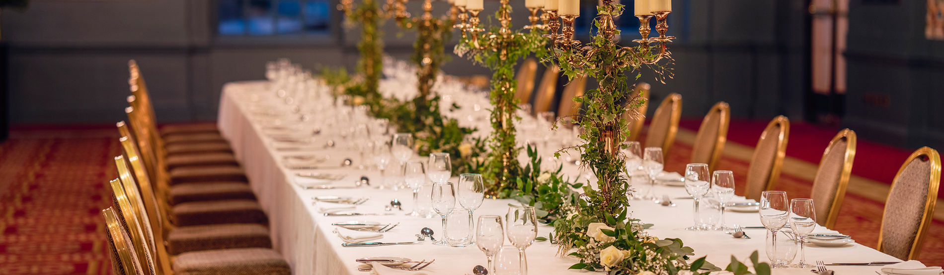 A private event setup in the George V Hall at The Bloomsbury, showcasing a candlelit long table with exquisite flower arrangements and sophisticated decor