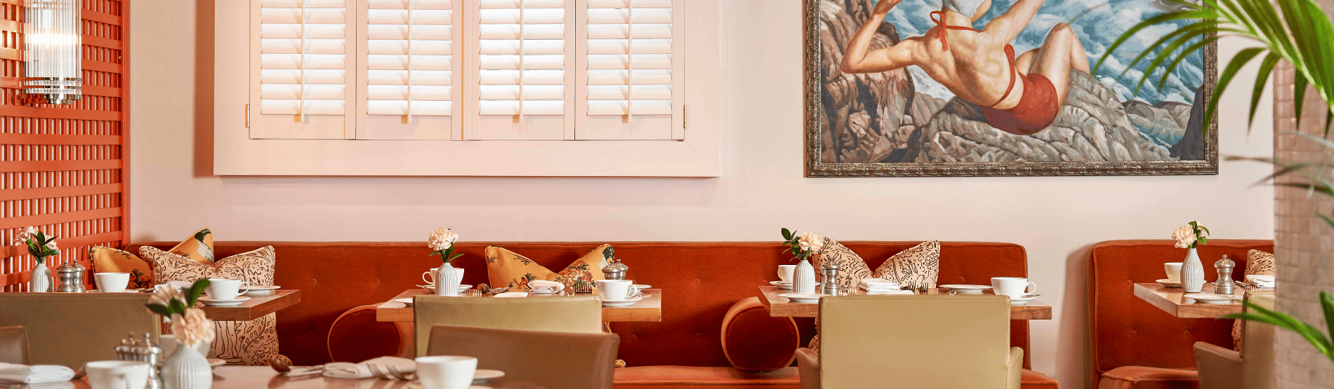 Trellis Room set for morning meeting breakfast, with orange accents on tables creating a stylish and energetic atmosphere for business gatherings.