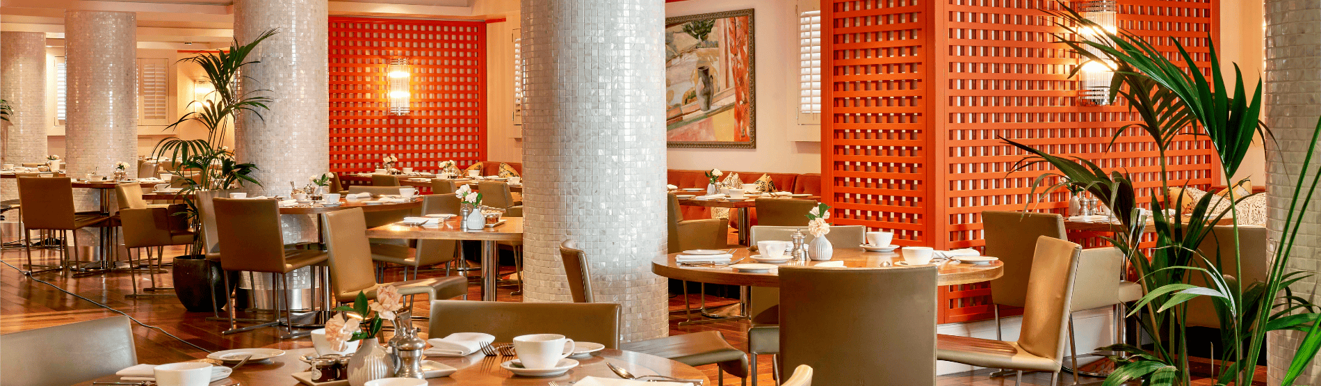 Trellis Room with tables set for breakfast, decorated with vibrant orange accents and a bright, welcoming atmosphere.