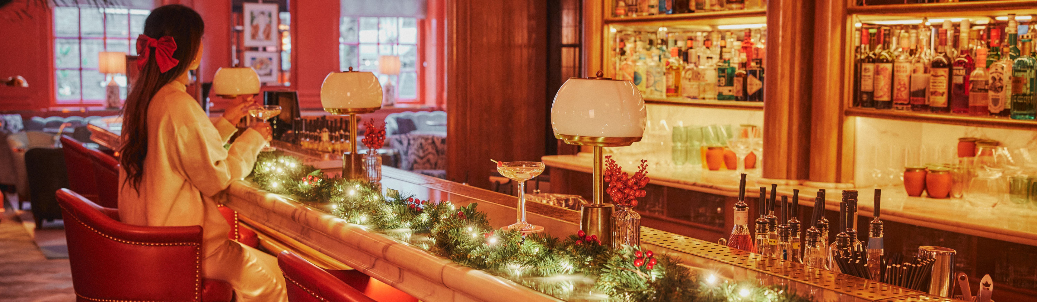 Festive holiday scene at The Bloomsbury Hotel: woman enjoying a martini at a  Christmas decorated bar in The Bloomsbury Hotel.