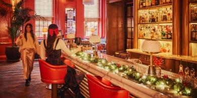 Festive holiday scene at The Bloomsbury Hotel: woman enjoying a martini at a Christmas decorated bar.
