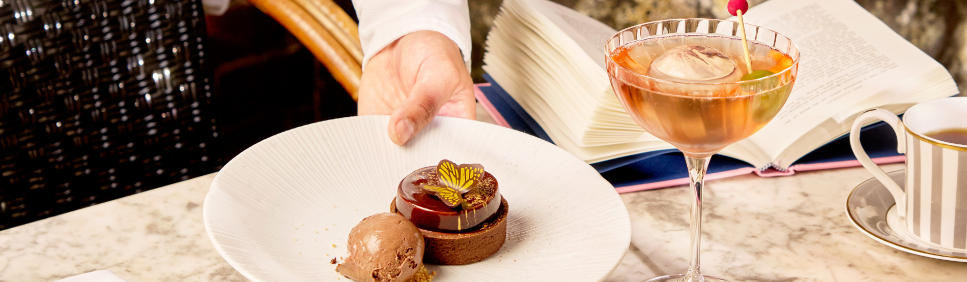 At Dalloway Terrace in the Bloomsbury hotel, a woman savors a cocktail and a sweet treat, with Mrs. Dalloway book open.