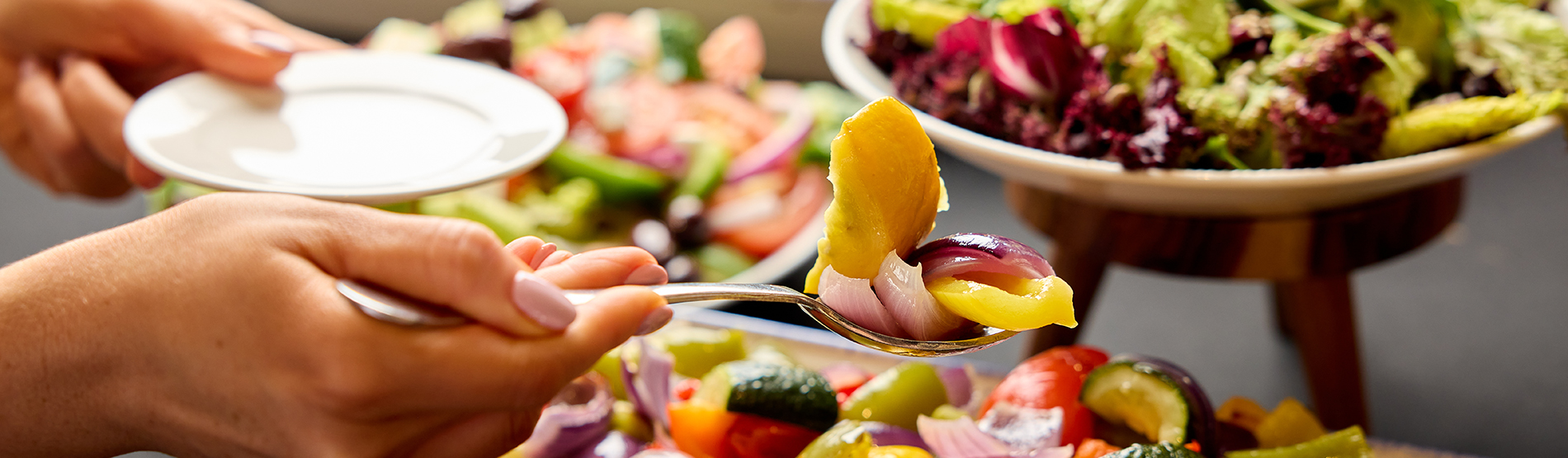 A savory buffet at the Bristol Hotel, with a wide selection of vegetables and salads. A hand is reaching into a dish.