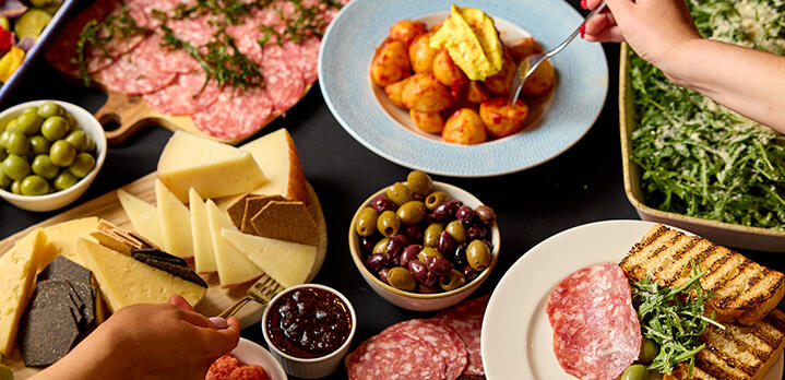 A buffet at Rick's restaurant in the Bristol Hotel, showing a variety of food with two hands reaching for dishes.