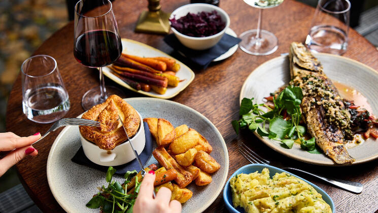 A beautifully presented 3-course pre-theatre dinner at The River Grille, featuring a savory pie, and fish and veggies, and two glasses of wine.