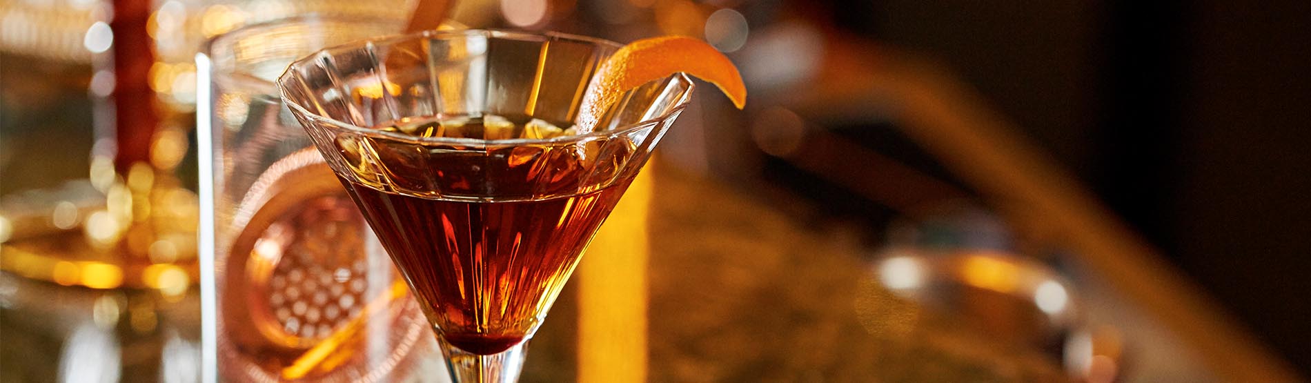 Cocktail in a martini glass with an orange peel garnish