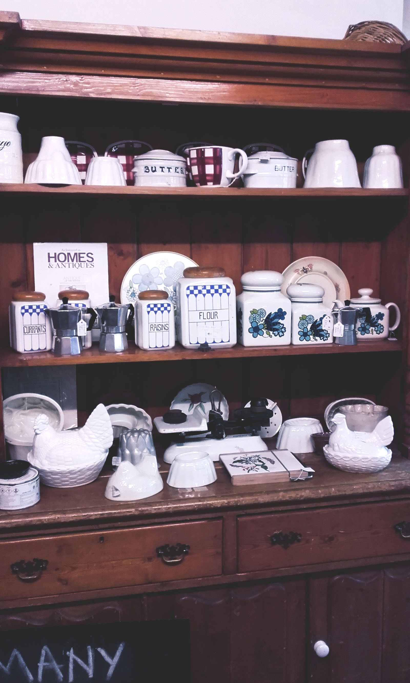 A wooden cabinet with three shelves filled with crockery 