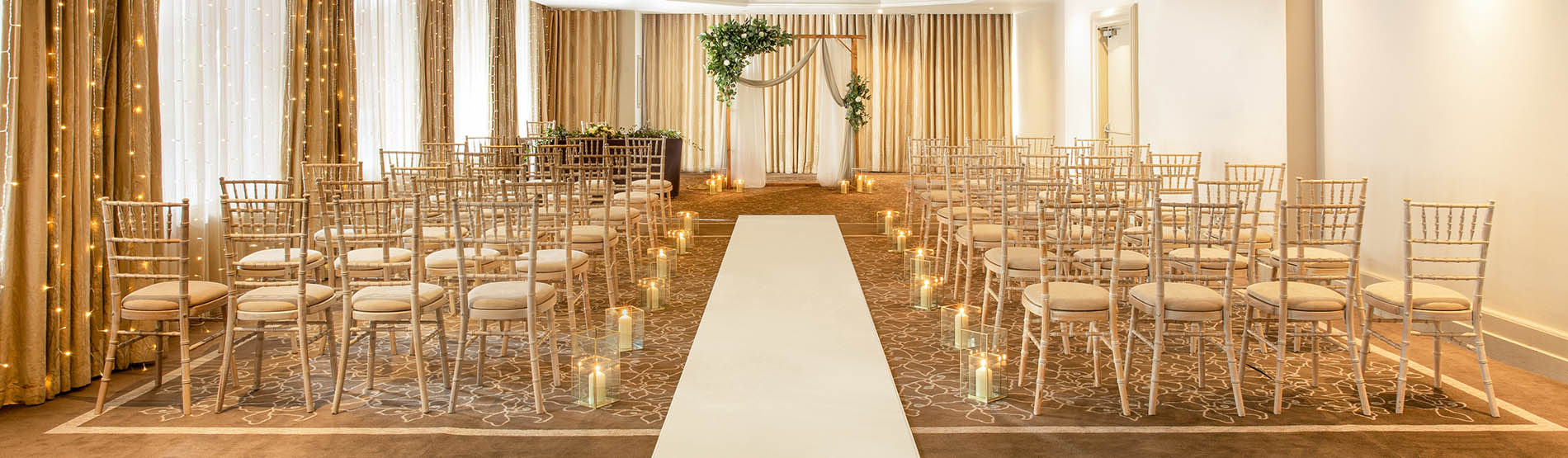 Candles lined white carpet in room set up for a civil ceremony