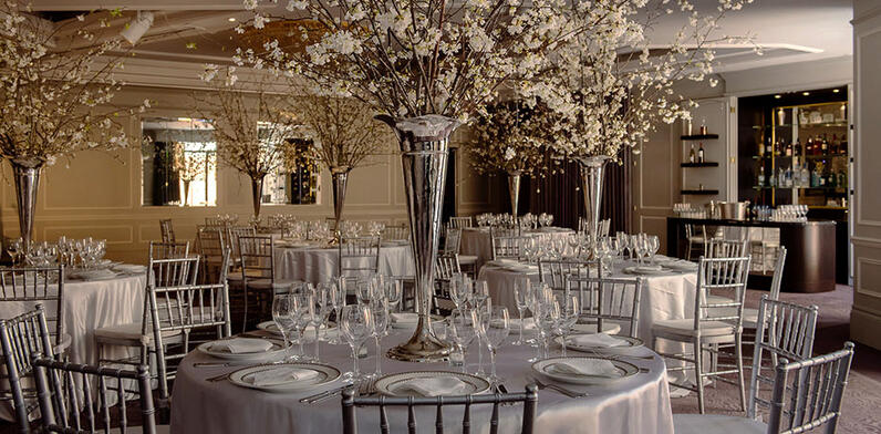 Round tables laid for a wedding breakfast with center piece of spring flowers