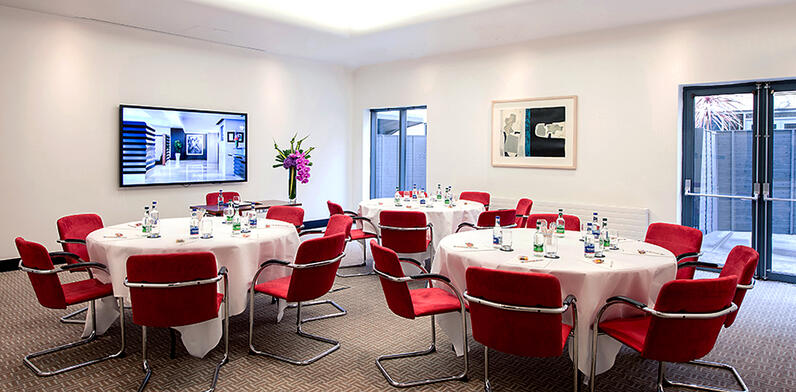 meeting room set up with round tables and red chairs
