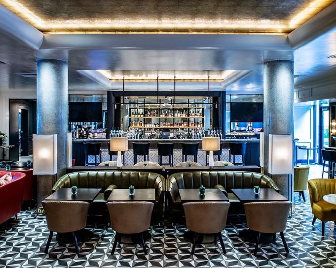 Interior of The Croke Park Hotel restaurant, showing the bar in the background and a mix of tables and sofas in the central view.