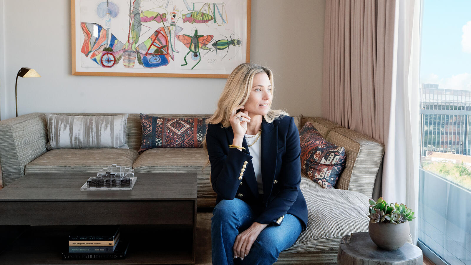 Veronica Beard in a navy blazer and jeans in the Dupont Circle hotel seated on a sofa inside the Penthouse Suite.