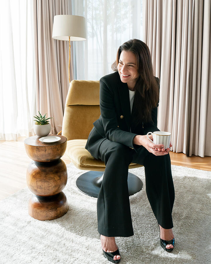 Veronica Beard in a navy blazer and jeans in the Dupont Circle hotel seated on a sofa inside the Penthouse Suite.