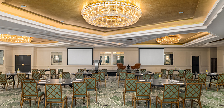 A bright and airy perspective of The Dupont Ballroom. Round tables with crescent seating create a collaborative yet focused environment, framed by the elegant architectural detail of the massive circular light fixture above.