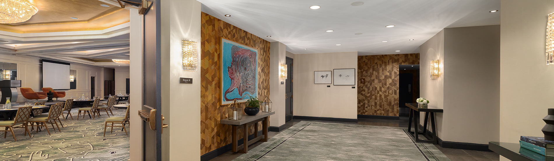 A wide-angle view of The DuPont Ballroom Foyer, showing a seamless transition into the ballroom. The foreground features the elegant, open pre-function space, leading the eye toward the ballroom’s grand interior and its signature circular ceiling lights.
