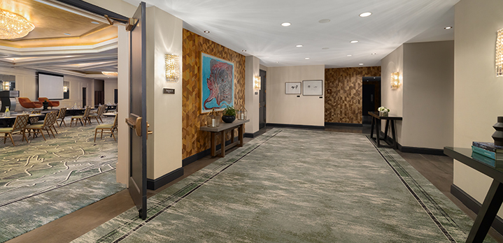 A perspective shot taken from the foyer looking into The Dupont Ballroom. The image captures the spaciousness of the entrance area and provides a clear view of the ballroom’s structured meeting setup and warm.