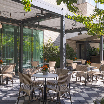 Outdoor seating on the Glover Park Terrace, featuring tables and chairs situated in a lush garden environment designed for casual breaks and relaxation.