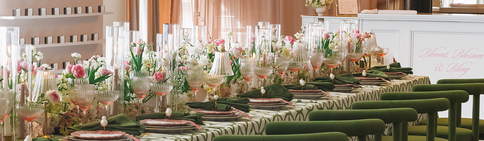 A beautifully styled long table set for a celebration in the Foxhall room, adorned with ornate pink flowers and green accents. The striking green chairs add a bold pop of color to the sophisticated pink-and-green event design.