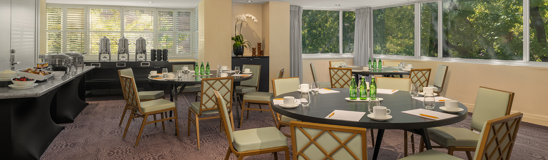 A comprehensive event setup in the Kalorama Room at The DuPont Circle. The image captures the transition from the collaborative round-table seating to a refreshing tea break station ideal for for a half-day or full-day seminar.