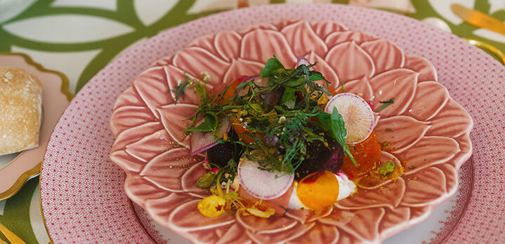 A salad and amuse-bouche served on a series of ornate pink plates.