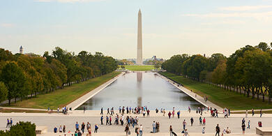 Visitors enjoying a sunny weekend in Washington, D.C., gathered around monument near popular tourist attractions.